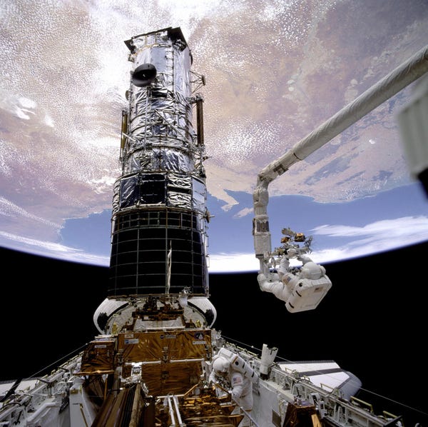 due astronauti in tuta spaziale lavorano sul telescopio spaziale Hubble nello spazio sopra la terra
