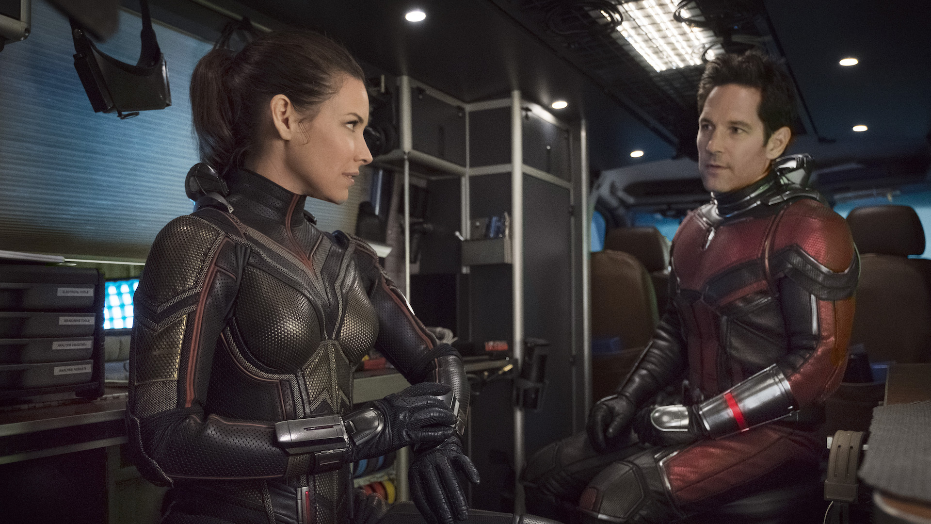 Hope (Evangeline Lilly) e Scott (Paul Rudd) parlano mentre indossano un'armatura di metallo futuristica.