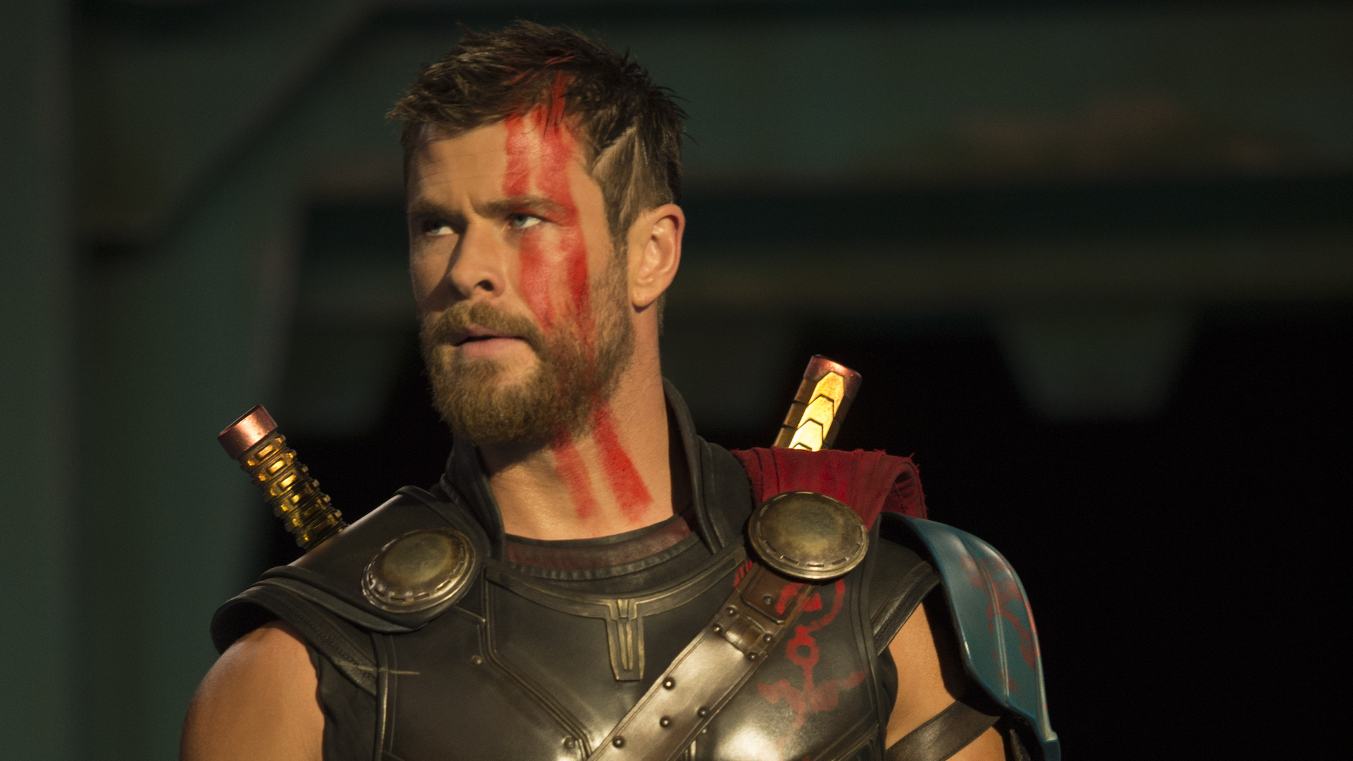 Un primo piano di Chris Hemsworth nei panni di Thor Odinson, con i capelli corti e la pittura di guerra rossa sul viso.