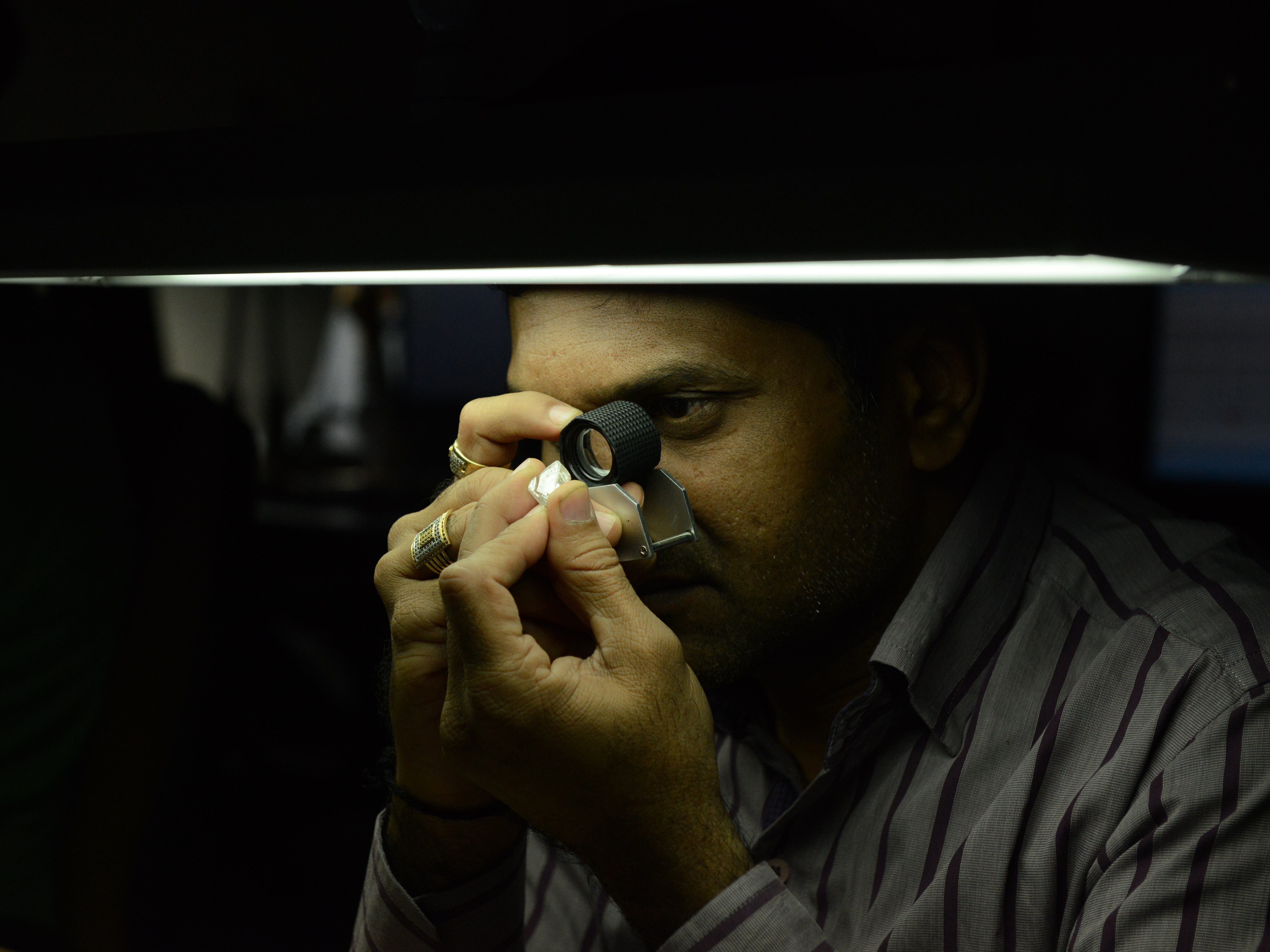 Un tecnico ispeziona un diamante grezzo in un'azienda manifatturiera a Surat, in India.