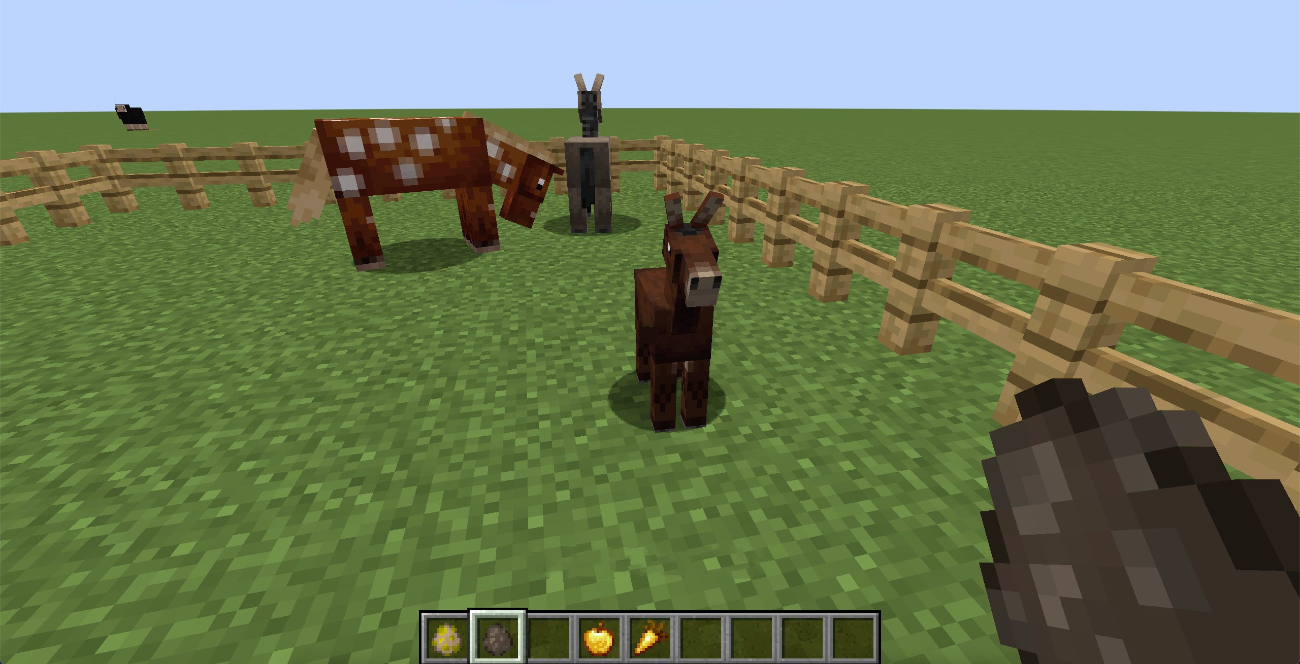 Uno screenshot del gioco Minecraft, che mostra un cucciolo di mulo in piedi vicino ai suoi genitori.