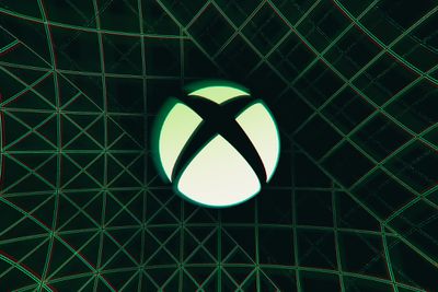 Il logo Xbox X in un cerchio su uno sfondo scuro con linee verdi.