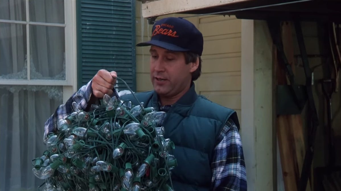 Un uomo tiene una palla di luci di Natale aggrovigliate.